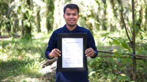 A smallholder farmer receives his certificate from the ISPO Secretariat